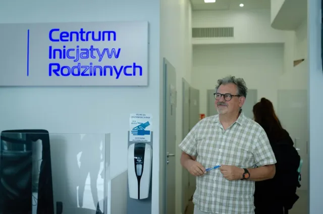 Mężczyzna stoi w holu Centrum Inicjatyw Rodzinnych, pod tablicą z nazwą placówki.