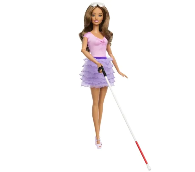 GPT Lalka Barbie z niepełnosprawnością wzroku. Ma długie brązowe włosy, ubrana jest w różową bluzkę z krótkim rękawem i fioletową, wielowarstwową spódniczkę. W jednej ręce trzyma białą laskę z czerwonym końcem, używaną przez osoby niewidome. Na głowie ma ciemne okulary przeciwsłoneczne.