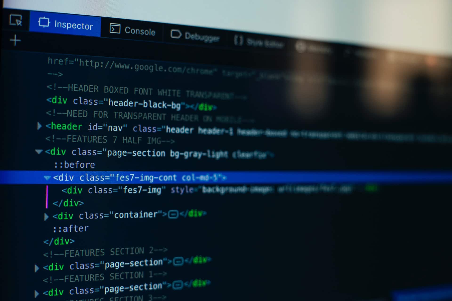 Ilustracją jest zdjęcie monitora, które na czarnym tle prezentuje fragmenty kodu HTML
