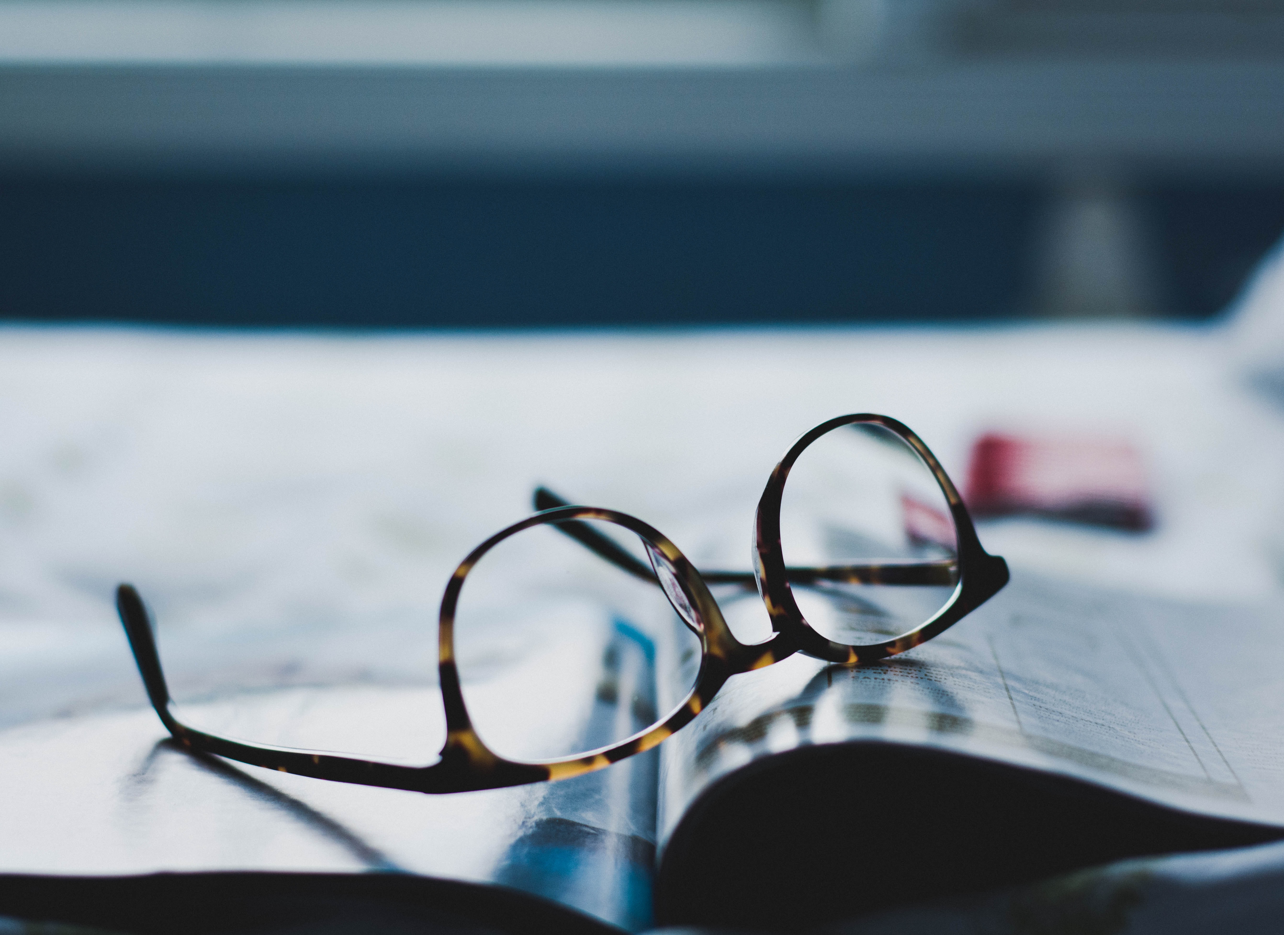 Obrazek przedstawia ujęcie na brązowe okulary położone na gazecie